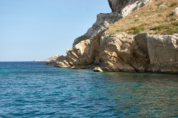 Fototapeta premium Boat trip through the Calanques of Marseille with blue waters and rock formations under a clear Mediterranean sky