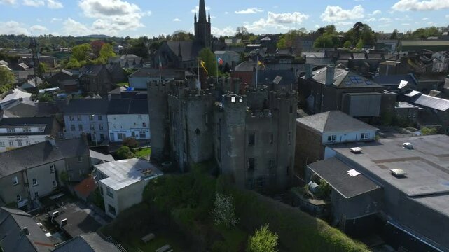 Enniscorthy Castle, County Wexford, Ireland, April 2025. Drone establishing orbit counterclockwise from backlit side to showcase swaying flags in wind as grand historic monument overlooks the town.