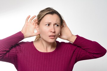 Woman cupping ears, straining to hear.
