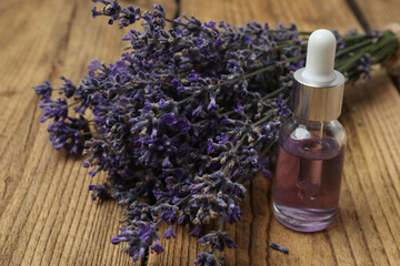 Bottles with lavender oil, lavender on wooden background