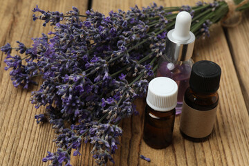 Bottles with lavender oil, lavender on wooden background