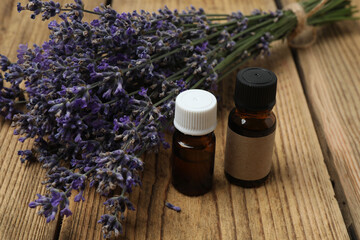 Bottles with lavender oil, lavender on wooden background