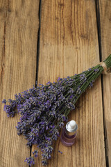 Bottles with lavender oil, lavender on wooden background