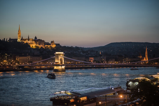 View of the Chain Bridge illuminated against the twilight sky over the Danube, with the Buda Castle district glowing in the distance, Budapest, Central Hungary, Hungary.