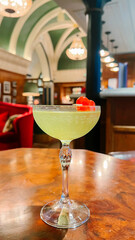 Elegant Green Cocktail with Cherry Garnish in Historic London Bar
