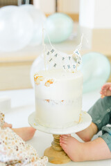 Partially eaten birthday cake with baby feet beside cake stand