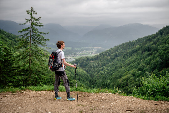 Male hiker with trekking poles admiring mountain view in Austria