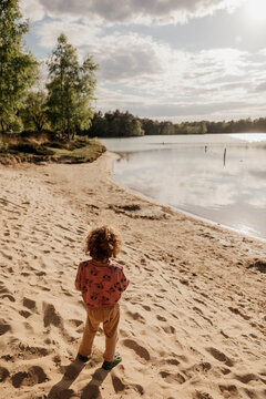 Children on a sandy lakeshore under soft golden sunlight