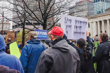 Faceless crowd marches to statehouse in protest with signs