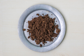 Top view of used black tea granules in silverware on wood. These repurposed tea granules serve as...