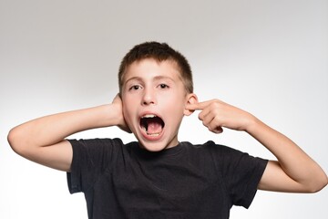 Boy covering ears and shouting, expressing frustration or annoyance.