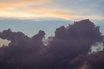 Dark storm clouds float across the afternoon sky, revealing a golden yellow glow behind them with hints of blue. Dramatic natural weather background.
