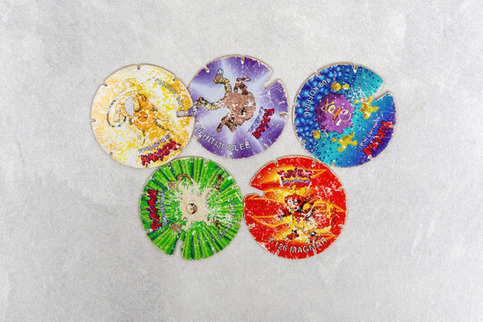 Vintage 1990s Pokemon Tazos. Small round collectible discs featuring original Pok&eacute;mon characters, often found in chip packets. Discolored and scratched retro kids toys.