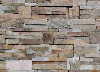 Multicolored external wall made of different types of rocks with different shapes. Background and...