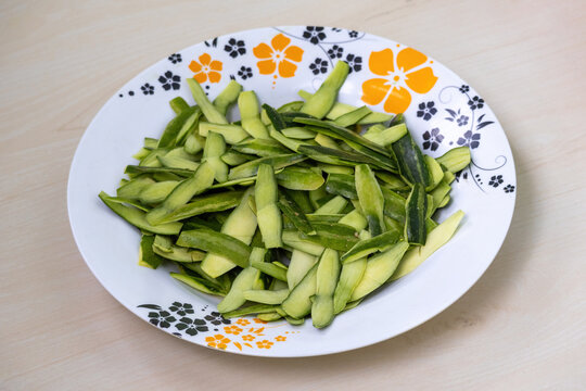 Fresh pointed gourd skin in melamine plate. Vibrant green Trichosanthes dioica, also known as parwal, potol, patol, or parval. Popular South Asian vegetable, perfect for healthy eating concepts.
