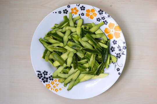 Fresh green pointed gourd skin (parwal, potol, patol, parval) in a melamine plate. Top view of this popular South Asian vegetable, perfect for healthy food concepts.