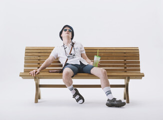 Middle-aged male tourist sitting on a bench, suffering from the heat. Concept of climate change.