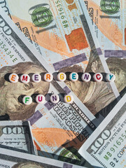 Concept image of emergency fund with dollar bills and colorful alphabet beads
