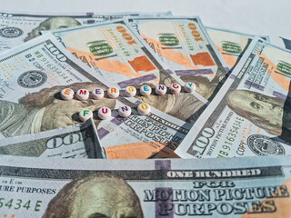 Concept image of emergency fund with dollar bills and colorful alphabet beads
