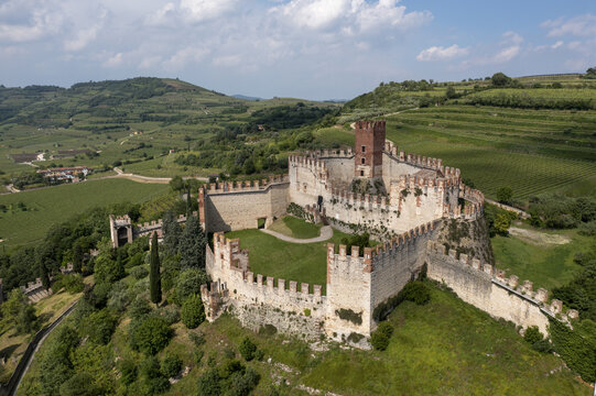 Aerial view of the ancient Castello Scaligero fortress standing proudly amid the vibrant green hills, a timeless sentinel overlooking the landscape, Castello Scaligero, Veneto, Italy.