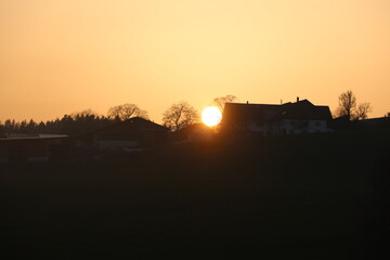 A sunset is reflected in the window of a house