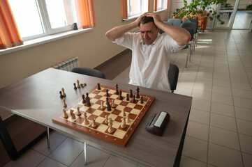 Caucasian man upset after losing chess game. 