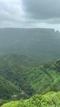 Beautiful landscape of King george point vally at Matheran, Maharashtra, India. Monsoon season rainy days with black clouds and lush greenary. Waterfall at one side and hills on other side in vally.