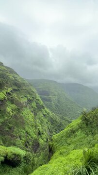 lush green mountain landscape with black clouds in monsoon weather.mountains are covered with green grass at matheran kadyvarcha ganpati point at maharashtra with fog and clouds