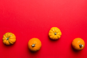 Autumn composition of little orange pumpkins on colored table background. Fall, Halloween and...