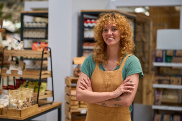 Confident saleswoman smiling with arms crossed in zero waste store