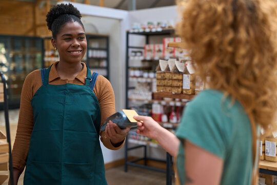 Smiling shop assistant accepting contactless payment from customer