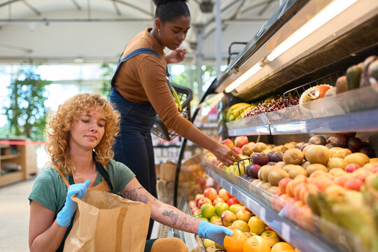 Grocery store workers filling shelves with fresh fruit