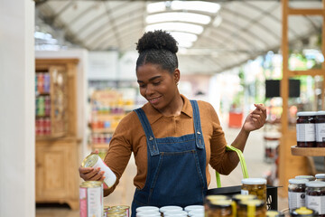 Grocer organizing canned goods on supermarket shelf