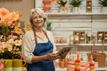 Senior florist managing inventory with digital tablet in flower shop