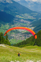 Colorful paraglider launching above Alpine valley, scenic summer mountain view. High quality photo