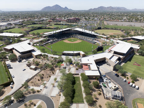 Aerial view of Salt River Fields at Talking Stick, a verdant baseball stadium nestled among the arid landscape, a striking contrast against the distant mountains, Scottsdale, Arizona, United States.