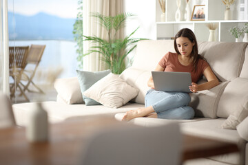 Woman using laptop sitting on a sofa in the living room