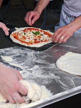 Przygotowanie tradycyjnej pizzy neapolitańskiej &ndash; nakładanie ciasta z sosem i serem na łopatę piekarską