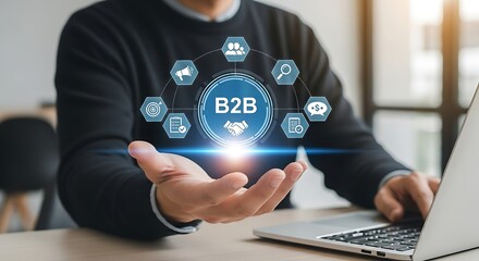 Emanating blue B2B concept hovers above outstretched palm warm glow infusing the digital icons on desk with laptop