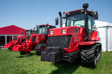 Fototapeta premium Three red tractors are parked in a field