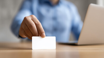 Farewell gesture from employee holding blank card near laptop on wooden desk in office setting