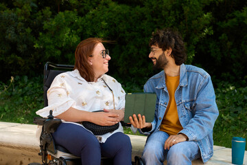 Smiling friends sharing a moment of joy and connection in the park - wheelchair and disability...
