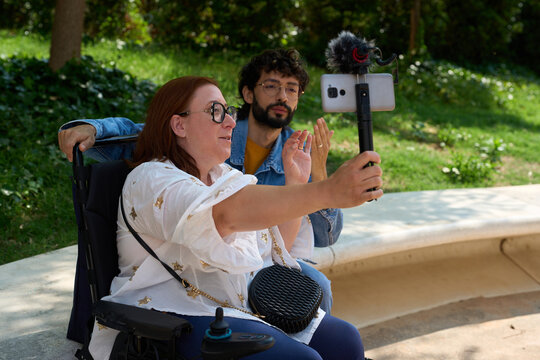 Content creators with disability recording video in park - wheelchair and disability concept