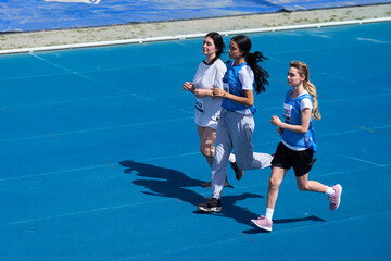 Female athletes running on blue track during competition
