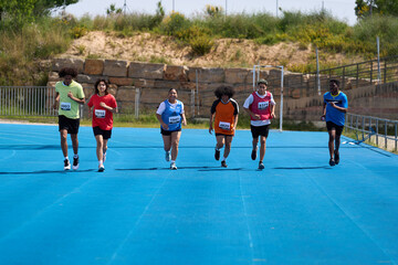Six young athletes running on blue track