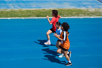 Female athletes running on blue track during competition