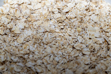 Imagen macro de copos de avena crudos, un alimento natural, nutritivo y rico en fibra. / Macro shot of raw rolled oats, a natural, nutritious, and fiber-rich food.
