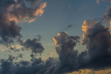 Colorful clouds during sunset create a dramatic sky above a serene landscape illuminating the...