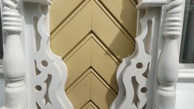 Carved decoration of facade of building. Close-up of sawn thread. White trim panels openwork carving on windows of yellow house. Fretwork