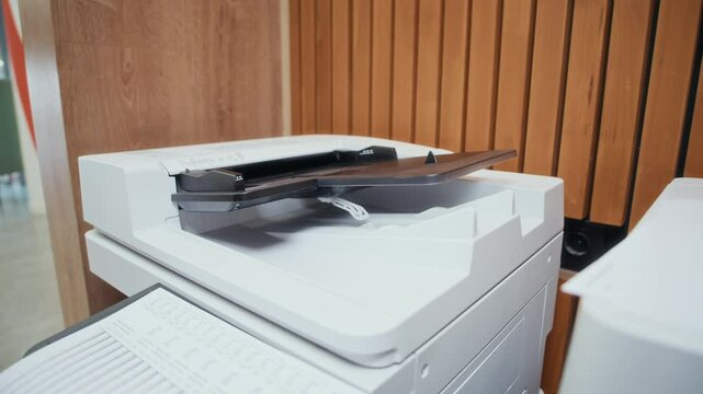Close up shot of hands of unrecognizable man using multifunction printer to make copies of documents while working in office